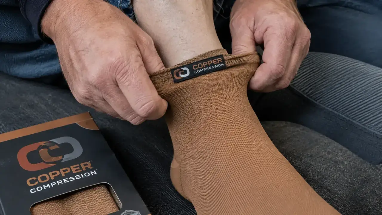 Hands pulling on copper-colored compression sock over bare foot and ankle