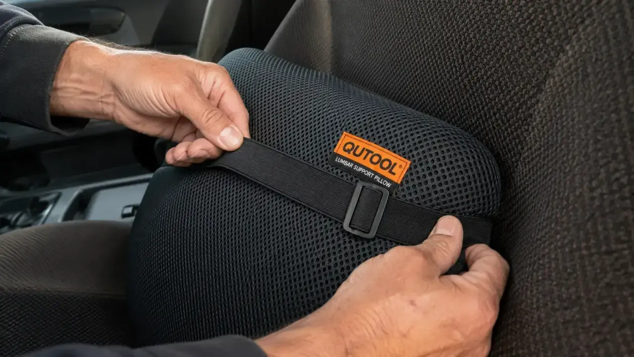 Hands positioning the QUTOOL lumbar pillow on a truck seat, adjusting the dual elastic straps
